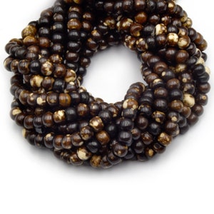 May include: A strand of brown and white wood beads. The beads are round and have a natural, rustic look.