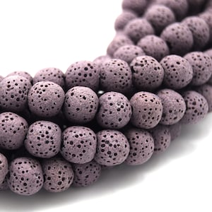 May include: A strand of purple lava rock beads. The beads are round and have a porous texture.