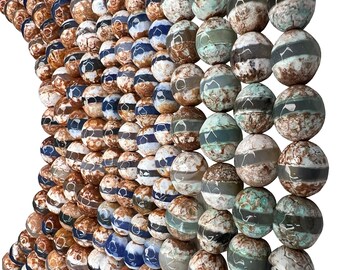 Op de afbeelding: Een verzameling bolvormige kralen gerangschikt in rijen, met een mix van bruine, witte en blauwgroene marmerpatronen. Elke kraal heeft een horizontale band van een effen kleur, wat zorgt voor een getextureerd uiterlijk over het oppervlak.