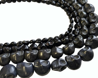 May include: A close-up of a strand of black skull beads. The beads are made of a smooth, polished material and have a slightly textured surface. The beads are arranged in a circular pattern, creating a necklace or bracelet.