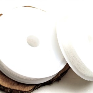 以下が含まれることがあります： コーヒーまたは紅茶用の白い丸い紙フィルターのスタックが、素朴な木製の表面に置かれています。 フィルターは清潔で明るく、滑らかな質感です。 画像は明るく、製品のシンプルさを際立たせています。