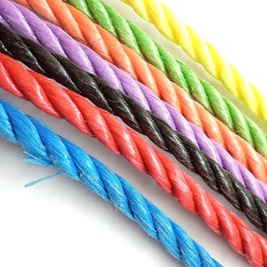 May include: Close-up of colourful twisted rope strands. The ropes are in various colours, including blue, red, black, purple, orange, green, and yellow. The ropes are tightly twisted and have a slightly glossy appearance. The background is white.