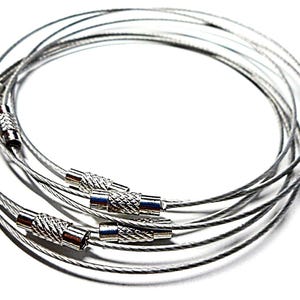 Può includere: Una collezione di portachiavi in filo d'acciaio argentato con chiusure metalliche strutturate. I portachiavi sono disposti in un motivo circolare su sfondo bianco, mettendo in risalto la loro lucentezza metallica e il design.