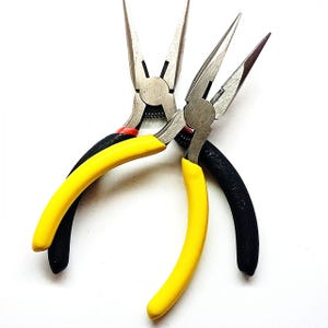 Peut inclure: Deux pinces à bec effilé avec des poignées jaunes et noires. Les pinces ont de longues mâchoires pointues et sont en métal. Une poignée est jaune, l'autre est noire. Les pinces sont conçues pour un travail de précision.