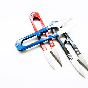 Peut inclure: Trois coupe-fils avec des lames métalliques tranchantes et des poignées colorées. Une paire a une poignée bleue, une a une poignée rouge et une a une poignée noire. Chaque outil dispose d'un mécanisme à ressort et de deux rivets sur les lames.