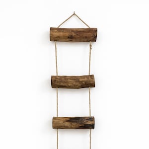 May include: A wooden ladder with four horizontal steps, suspended by rope. The ladder is made from weathered wood, displaying natural grain and knots. The design is simple and minimalist, suitable for decorative purposes. The ladder is suspended by rope.