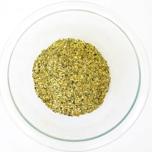 Peut inclure: Un bol en verre transparent rempli de feuilles de maté vert séchées.