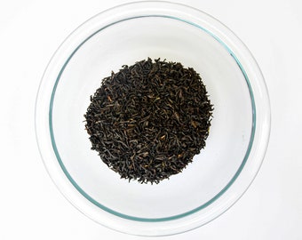 May include: A glass bowl filled with loose black tea leaves.