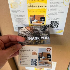 May include: A Sourdough Starter Kit box with an informational insert listing contents like a 10-inch oval banneton, bread lame, dough whisk, and flour sifter. Two thank you cards from Hankerie are held in front, displaying contact details and QR codes.