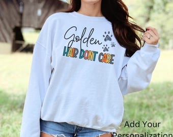 May include: White sweatshirt with the text "Golden Hair Don't Care" in colorful letters and paw prints.