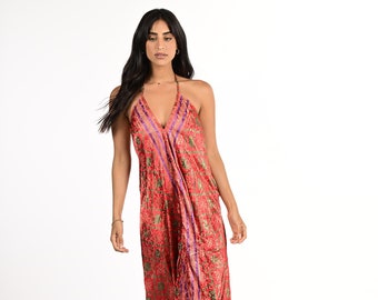 Puede incluir: Una mujer lleva un vestido largo de tirantes rojo con estampado floral y detalles en morado y dorado. El vestido tiene un corte holgado y fluido y está hecho de una tela suave y sedosa.