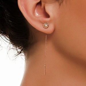 以下が含まれることがあります： 小さな花のチャームと繊細なチェーンが細いバーまで伸びている、ローズゴールドのドロップイヤリングです。