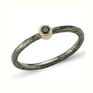 May include: A silver ring with a hammered texture and a black gemstone set in a gold bezel.