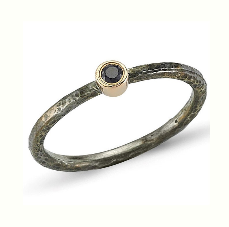 May include: A silver ring with a hammered texture and a black gemstone set in a gold bezel.