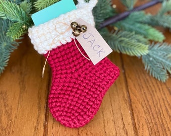 May include: A small red crocheted stocking with a white cuff, filled with a gift card and a tag that says "JACK".