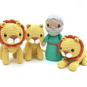 May include: Three crocheted stuffed animals: a man with a gray beard and a green robe, and two yellow lions with orange manes.