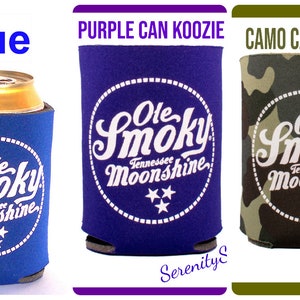 Pu&ograve; includere: Cinque diversi refrigeratori per lattine di diversi colori con il logo "Ole Smoky Tennessee Moonshine" in lettere bianche su un cerchio bianco. I refrigeratori per lattine sono nero, blu, viola, mimetico e tie-dye.
