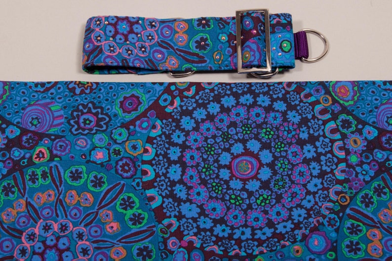 May include: A dog collar and matching fabric featuring a vibrant floral pattern in shades of blue, teal, purple, and pink. The collar has a silver-colored buckle and a purple loop for leash attachment.