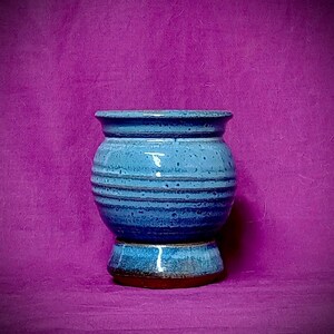 May include: A set of three ceramic mugs with a speckled, matte finish. Each mug is a different colour: light blue, cream, and grey. The mugs have a simple, modern design and a comfortable handle.