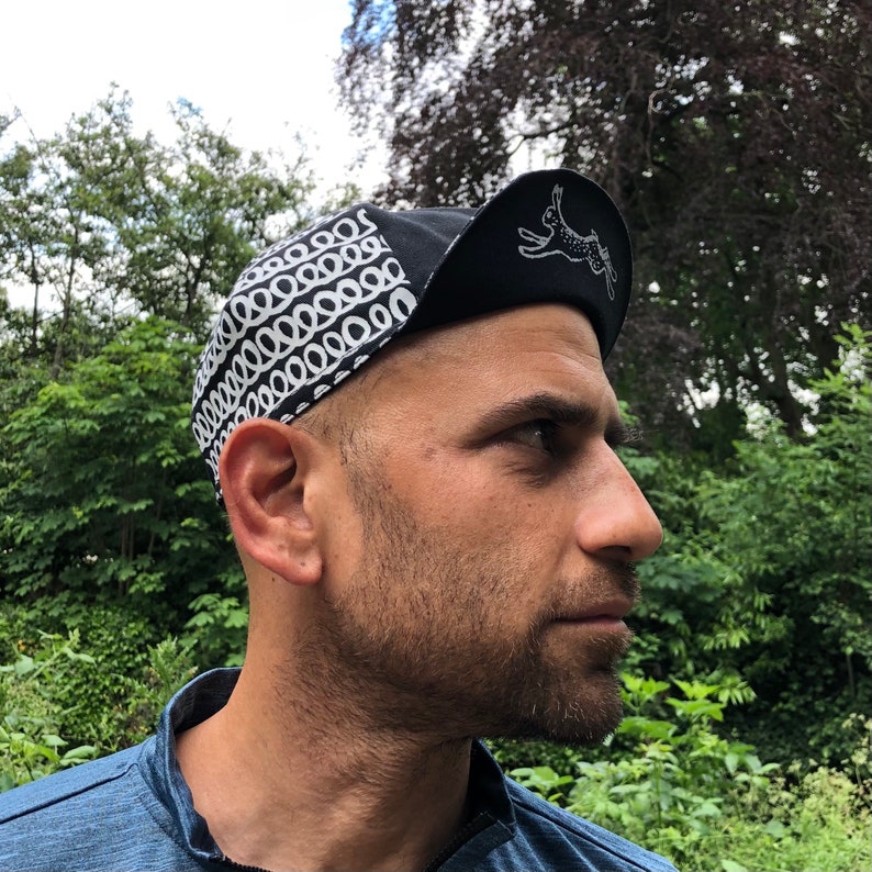 May include: A black and white cycling cap with a pattern of circles and a small white rabbit graphic on the side.
