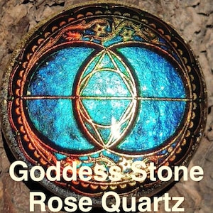 Op de afbeelding: Een ronde hanger met een blauw en goud ontwerp, met geometrische vormen en de tekst "Goddess Stone Rose Quartz Black Obsidian". De hanger heeft een goudkleurige beugel om op te hangen.