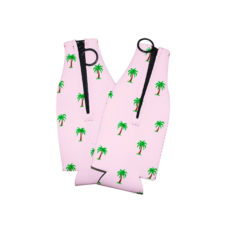 May include: Two pink neoprene can coolers with a zipper closure and a palm tree print.