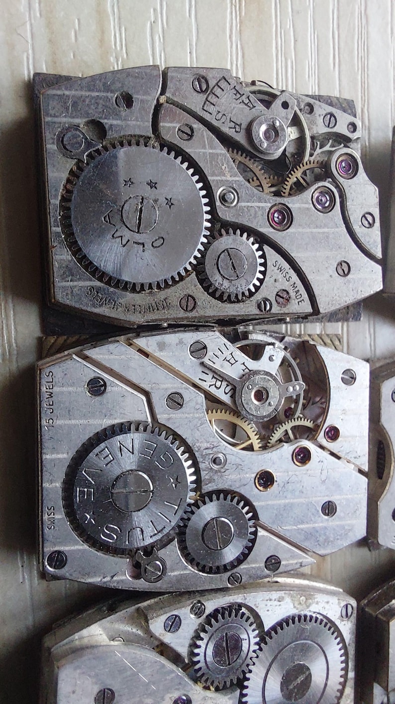 Peut inclure: Gros plan sur des mouvements de montre anciens, avec des engrenages, des bijoux et des inscriptions visibles. Les composants m&eacute;talliques sont agenc&eacute;s avec pr&eacute;cision, montrant la m&eacute;canique interne des montres. Les mouvements de montre sont marqu&eacute;s "SWISS MADE" et "15 JEWELS".