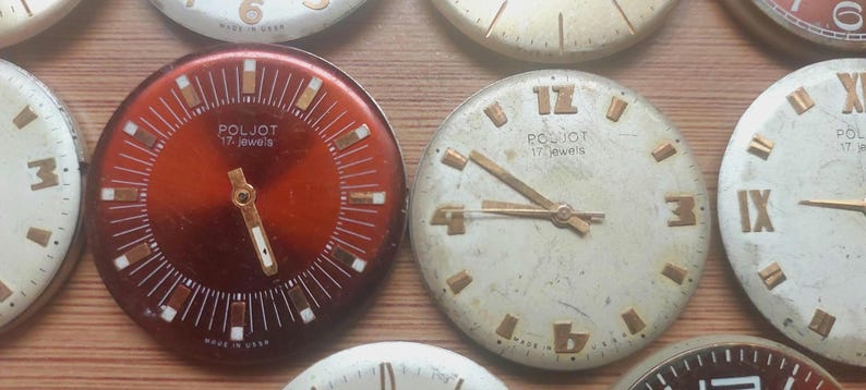Pode incluir: Uma cole&ccedil;&atilde;o de mostradores de rel&oacute;gios vintage com v&aacute;rios designs e cores. Os mostradores incluem algarismos romanos e ar&aacute;bicos, com ponteiros e marcadores dourados. Alguns mostradores t&ecirc;m a marca "POLJOT" e "17 jewels" impressos.