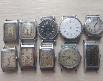 Può includere: Una collezione di orologi da polso vintage con vari design del quadrante e casse in metallo. Gli orologi presentano quadranti rettangolari e circolari, con numeri e lancette visibili. Alcuni hanno quadranti usurati.