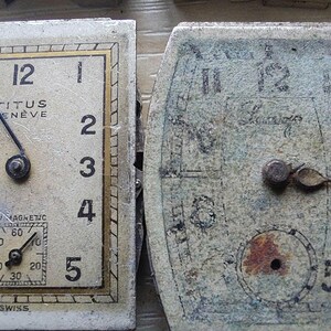 Peut inclure: Deux cadrans de montre vintage. Le cadran de gauche est rectangulaire avec le texte "TITUS GENEVE" et le mot "SWISS". Le cadran de droite est ovale et tr&egrave;s us&eacute;. Les deux cadrans affichent des chiffres et des aiguilles.