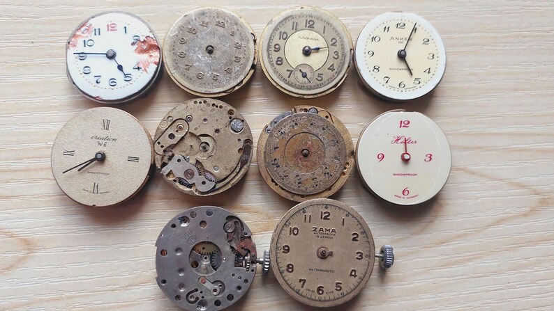 May include: A collection of vintage watch faces and movements, showcasing various designs and mechanical components. The dials feature Roman and Arabic numerals, with hands pointing to different times. Some have visible gears and internal mechanisms.