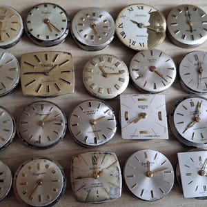 May include: A collection of vintage watch faces in various shapes, including round and square. The faces feature silver and gold tones, with visible hands and hour markers. Some have brand names like 'Longines' and 'Tressa'.