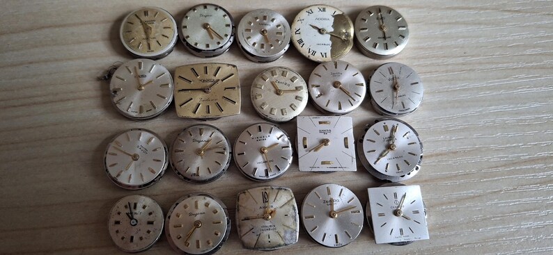 May include: A collection of vintage watch faces in various shapes, including round and square. The faces feature silver and gold tones, with visible hands and hour markers. Some have brand names like 'Longines' and 'Tressa'.