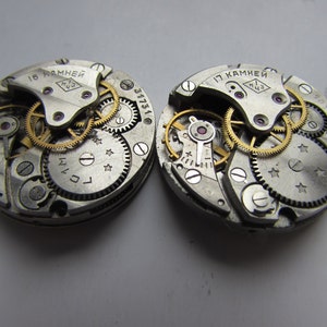 May include: Two silver watch movements with gold gears and screws. The text "15 камней" and "17 камней" is visible on the top of each movement.