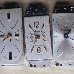 May include: A collection of vintage watch faces, showcasing various designs and brands. The faces feature Roman and Arabic numerals, with hands indicating the time. Brands include Dulux, Montine, and others. The watch faces are in various shapes and colors.