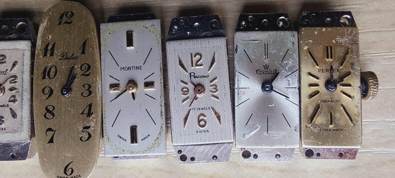 May include: A collection of vintage watch faces, showcasing various designs and brands. The faces feature Roman and Arabic numerals, with hands indicating the time. Brands include Dulux, Montine, and others. The watch faces are in various shapes and colors.