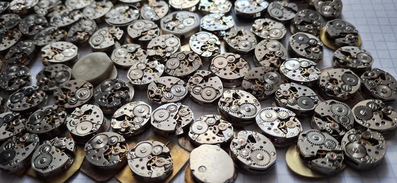 May include: A collection of vintage watch movements, showcasing intricate gears and mechanical components. The silver-toned metal parts are arranged in a scattered pattern, highlighting the detailed craftsmanship of each piece. Ideal for steampunk projects or watch repair.