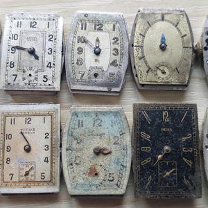 Peut inclure: Une collection de cadrans et de mouvements de montres vintage, pr&eacute;sentant diverses formes et designs. L'assortiment comprend des cadrans rectangulaires, ovales et carr&eacute;s avec des chiffres romains et arabes, et des m&eacute;canismes internes visibles. Les couleurs sont patin&eacute;es.