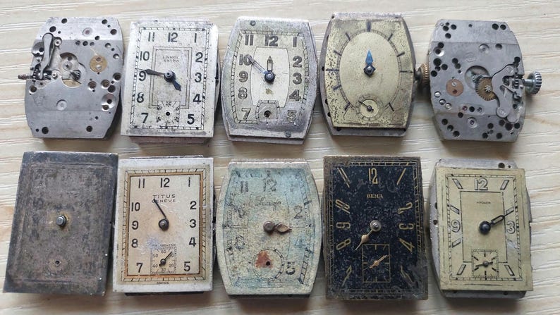 Peut inclure: Une collection de cadrans et de mouvements de montres vintage, pr&eacute;sentant diverses formes et designs. L'assortiment comprend des cadrans rectangulaires, ovales et carr&eacute;s avec des chiffres romains et arabes, et des m&eacute;canismes internes visibles. Les couleurs sont patin&eacute;es.