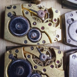 Puede incluir: Primer plano de movimientos de relojes antiguos con intrincados engranajes, tornillos y joyas. Los componentes met&aacute;licos dorados presentan la marca "Jaco" y los n&uacute;meros "580" y "550". La imagen muestra la detallada mec&aacute;nica de los relojes antiguos.