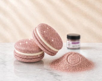Könnte beinhalten: Zwei roségoldene, glitzernde makronenförmige Dekorationen mit weißer Füllung, begleitet von einem kleinen Glas mit schwarzem Deckel und einem Haufen losem roségoldenem Glitzer mit dem geprägten Text Oh Sweet Art.