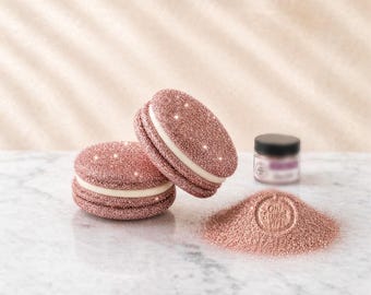 Könnte beinhalten: Zwei mit roségoldenem Glitzer bedeckte makronenförmige Dekorationen mit einer weißen Mittelschicht, begleitet von einem kleinen Glas mit schwarzem Deckel und einem Haufen losem roségoldenem Glitzer mit dem Prägetext Oh! Sweet Art.