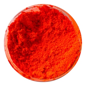 May include: A circular container filled with a vibrant, neon orange pigment powder. The fine, loose substance has a textured, granular appearance and fills the clear vessel completely, displaying a bright, saturated, and uniform color throughout.