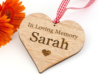May include: Wooden heart-shaped ornament with a red and white checkered ribbon. The ornament is engraved with the text "In Loving Memory Sarah" and a small heart.