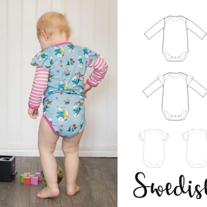 Puede incluir: Un bebé con un body de manga larga azul y rosa con un estampado de dibujos animados. El body tiene mangas con volantes. El bebé está de pie sobre un suelo de madera. La imagen también incluye un dibujo de línea de un body similar con mangas con volantes.