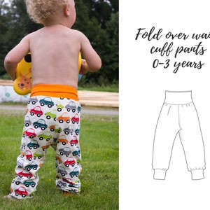 May include: A white pair of fold-over waist cuff trousers with a colourful car print. The trousers are designed for children aged 0-3 years. The text "Fold over waist cuff pants 0-3 years" is printed on a white background.