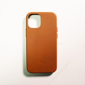 May include: A brown leather phone case with a gold trim and the word "alpa" embossed on the back.