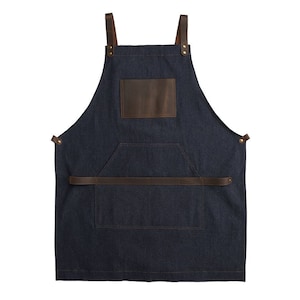 May include: A dark blue denim apron with a brown leather patch and a brown leather strap across the front. The apron has a large pocket on the front.