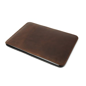May include: A brown leather laptop sleeve with a subtle distressed look.