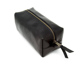 May include: Black leather zippered toiletry bag with a gold zipper pull.